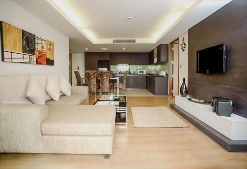 a living room with a couch and a kitchen at Olive Hotel & Residence Bangkok Sukhumvit 101 in Bangkok