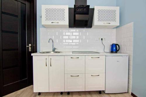 a white kitchen with a sink and a stove at квартира на Ангиса in Itʼkhvisi