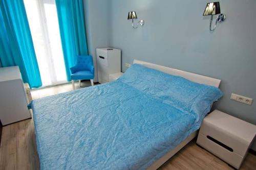 a bedroom with a bed with a blue comforter at квартира на Ангиса in Itʼkhvisi