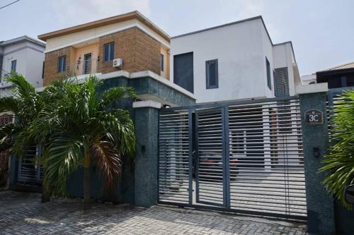 a house with a gate and a palm tree in front of it at The Residence 6 in Lekki