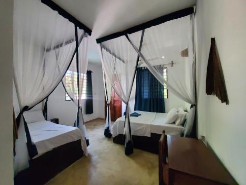a bedroom with two beds with mosquito netting at Nionje Garden Villa in Jambiani