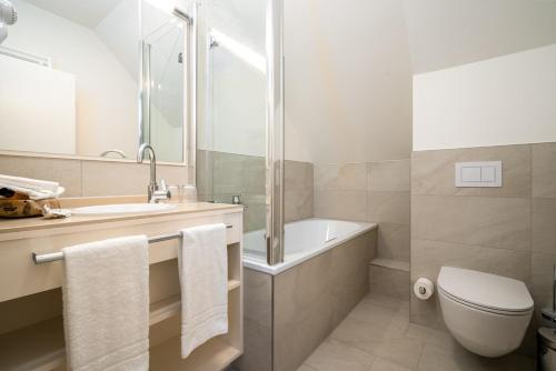 a bathroom with a tub and a toilet and a sink at Hotel Villa am Stadthafen in Neustrelitz