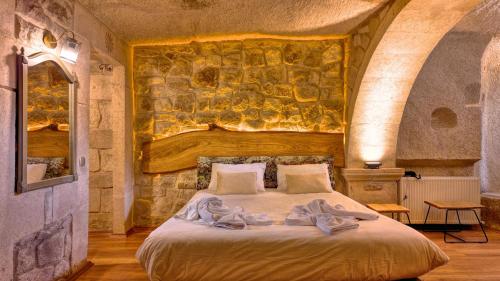 a bedroom with a large bed with a stone wall at Anjelic Cave Cappadocia in Urgup