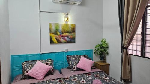 a bedroom with a bed with pink pillows and a painting at Rumah Inap Haziq in Seri Manjung