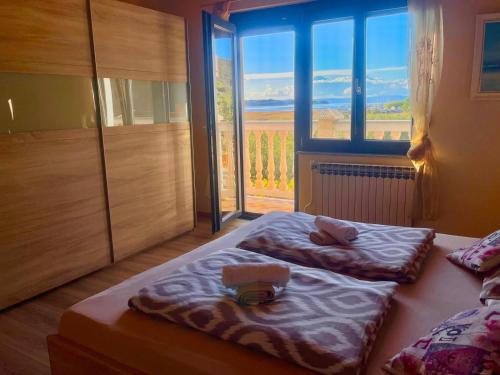 two beds in a room with a large window at Apartment Vesna in Supetarska Draga