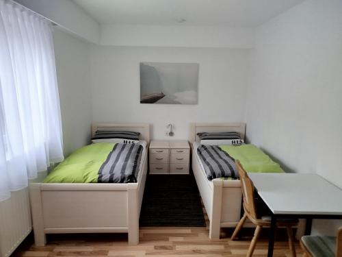 two beds in a room with a table and a desk at Gästehaus Kreuz in Blaustein