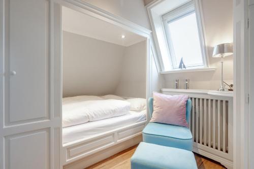 a small bedroom with a bed and a blue chair at Wattküken in Munkmarsch