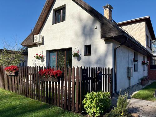 una casa bianca con recinzione e fiori di Cozy village a Ikšķile