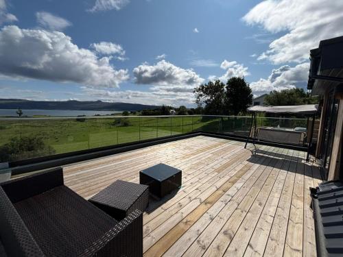 a deck with a couch and a view of the water at Luxurious, Unique & Elegant Cottage in Portree in Ollach