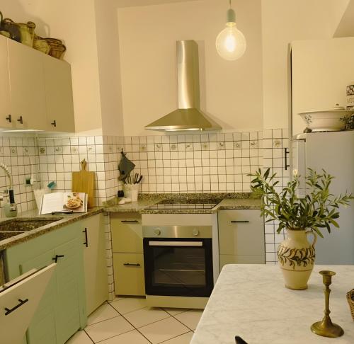 a kitchen with green cabinets and a vase with a plant at Sbilenca Sbilenchina - Charming Houses, Garden & BBQ for Climbers, MTB Lovers & Families in Calice Ligure