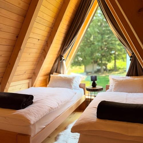 two beds in a room with a large window at Villa Alba in Kupres