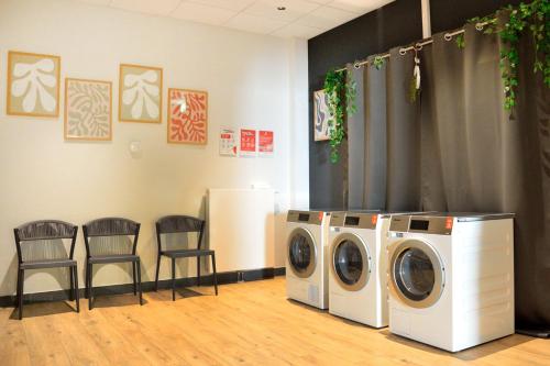 a laundry room with two washing machines and two chairs at Candlewood Suites Augsburg in Augsburg