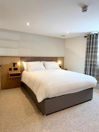 a bedroom with a large bed with white sheets at Cross Pipes Tavern and Rooms in Otley