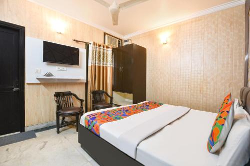 a bedroom with a bed and a chair and a tv at FabExpress Grand Highway in Faridabad