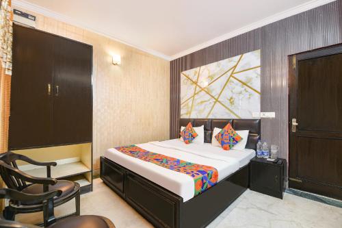 a bedroom with a bed and a chair in it at FabExpress Grand Highway in Faridabad