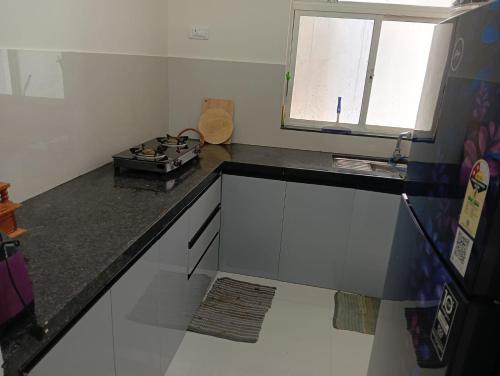 Una cocina con encimera negra y ventana. en Homestay 2Bhk, en Hinjawadi