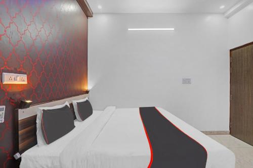 a bedroom with a white bed with a red wall at Collection O Shivashakti Grand Near Chaudhary Charan Singh International Airport in Banthra Sikandarpur