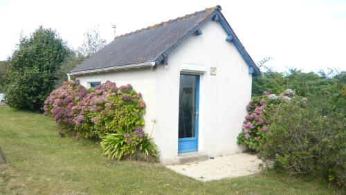 a small white house with a blue door and flowers at Châtaigne in Plouézec