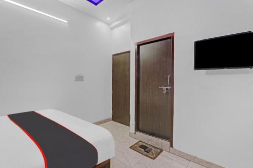 a room with a bed and a tv and a door at Collection O Shivashakti Grand Near Chaudhary Charan Singh International Airport in Banthra Sikandarpur