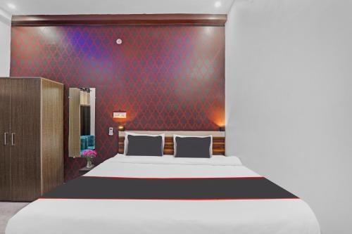 a bedroom with a bed and a red wall at Collection O Shivashakti Grand Near Chaudhary Charan Singh International Airport in Banthra Sikandarpur