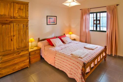 1 dormitorio con 1 cama grande con almohadas rojas en Cabañas Dolce Vita I en Los Reartes