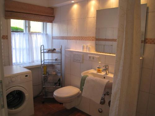 a bathroom with a toilet and a sink and a washing machine at Welkimen tüs 1-Tradition in Oldsum