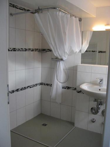 a bathroom with a sink and a shower curtain at Welkimen tüs 2-Moderne in Oldsum