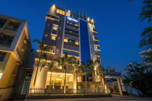 a tall building with palm trees in front of it at FabHotel The Botanica- Nr Hmwssb Kondapur section office-Masjid Banda, Kondapur in Kondapur