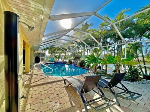a swimming pool with two chairs and an umbrella at Villa Malibu in Cape Coral Hospital Heliport