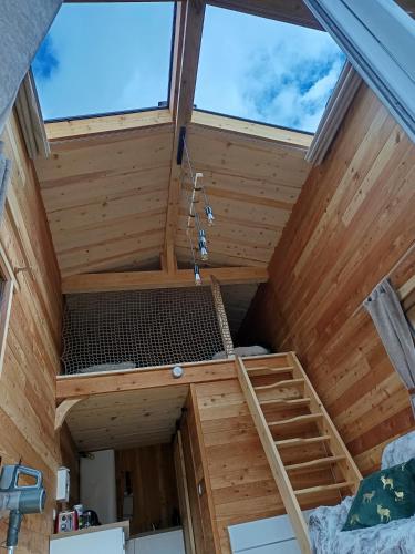 a loft bed in a tiny house with two windows at L'ânon d'Andon in Andon