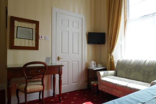 a hotel room with a couch and a table and a door at Ashgrove House in Edinburgh