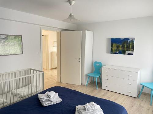 a bedroom with a crib and a blue chair at SUITE DOLOMITI Appartamento in Falcade