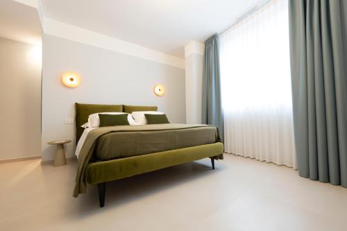 a bedroom with a green bed and a large window at In Piazza BnB in San Salvo