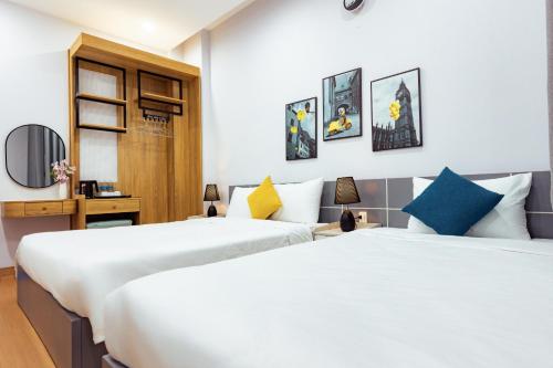 two beds in a room with white walls at Sunshine Hotel in Buon Ma Thuot