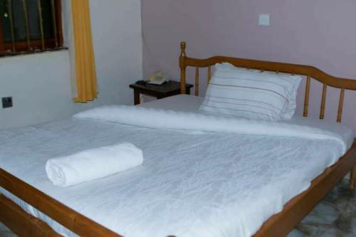 a bed with a wooden headboard with a towel on it at Gorilla African Guest House in Entebbe