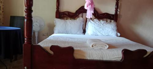 a bed with a wooden frame with a pink doll on it at Gorilla African Guest House in Entebbe