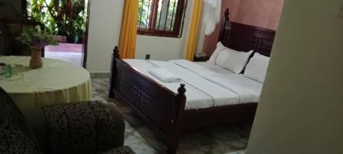 a bedroom with a bed and a table and a chair at Gorilla African Guest House in Entebbe