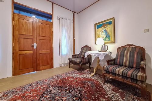 a living room with two chairs and a table and a door at Urbanview Onengan Resort in Palang-Putih