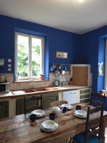a kitchen with a wooden table and a blue wall at Chateau Le Vieil Etang in Saint-Sauveur-le-Vicomte