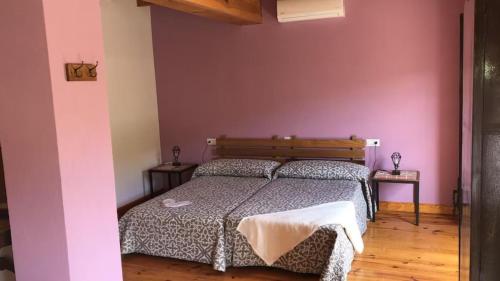 Un dormitorio con una cama y una pared rosa. en Gran Casa de Montana, en Fornells de la Muntanya