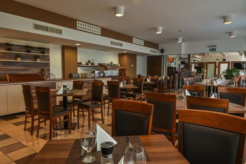 a restaurant with tables and chairs and a bar at Hotel Opal Superior - Adults Only in Gyöngyös