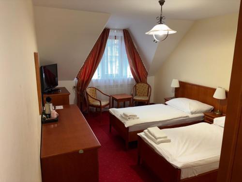 a hotel room with two beds and a desk at Penzion 77 - Garni in Pezinok