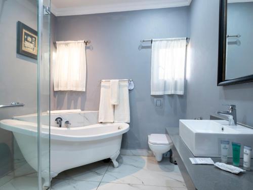 a bathroom with a tub and a sink and a toilet at ANEW Resort Ingeli Forest Kokstad in Kokstad