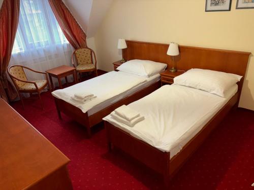 a hotel room with two beds and a table and chairs at Penzion 77 - Garni in Pezinok