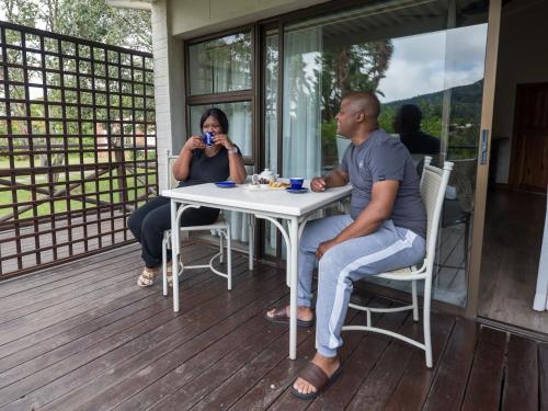 a man and a woman sitting at a table on a porch at ANEW Resort Ingeli Forest Kokstad in Kokstad