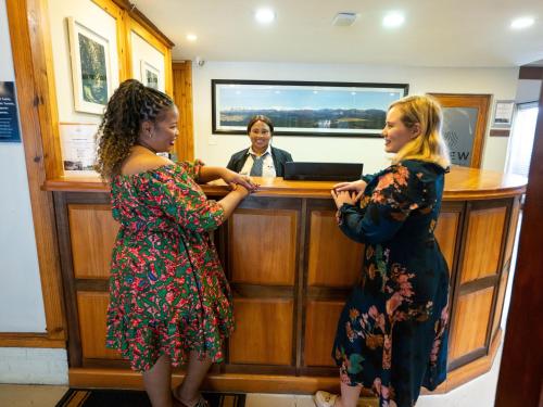 two women standing in front of a bar with a man at ANEW Resort Ingeli Forest Kokstad in Kokstad