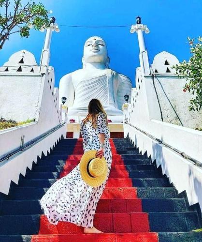 a woman walking down a staircase in front of a large statue at Kandy View Stay in Kandy