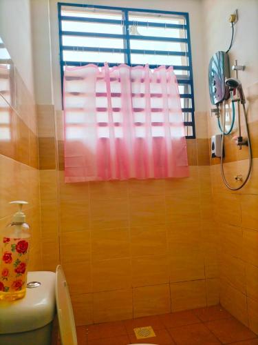 a bathroom with a pink shower curtain and a toilet at Homestay Ustaz in Batu Gajah