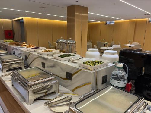 a buffet line with plates of food on display at 比什凯克水晶轻奢智享酒店阿拉套广场店Bishkek Crystal Luxury Smart Hotel Ala-Too Square Branch in Bishkek