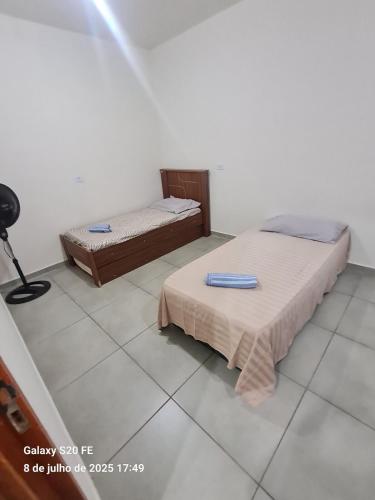 a bedroom with two beds and a lamp on the floor at La ville Guaxupe - Casa em Guaxupé in Guaxupé